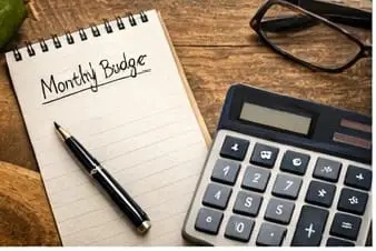 A household budgeting setup with calculator, notebook labeled budget, cash savings jar, and utility bills representing ways to save on daily expenses and manage monthly finances.